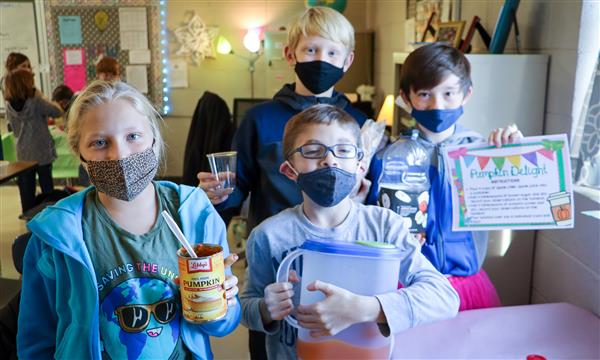 Students hold their science experiment supplies and smile